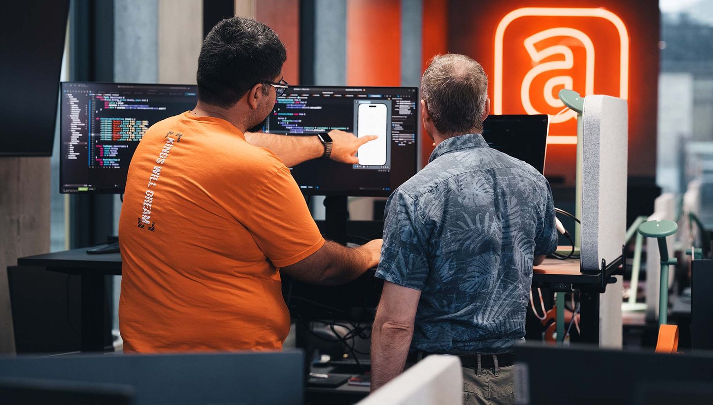 coworkers-talking-desk-multiple-screens