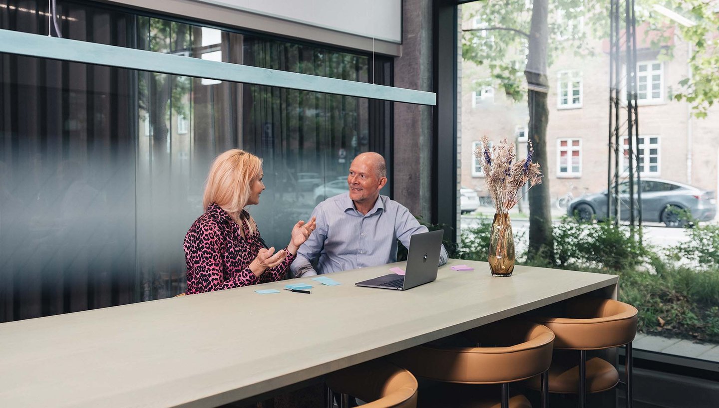 A finance controller reviewing digital expense reports on a laptop in a modern Danish office.