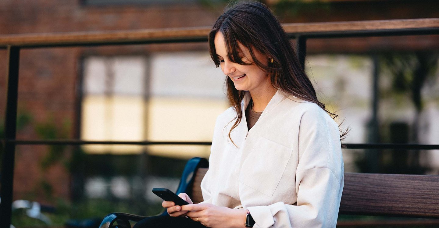woman-sitting-with-phone-outside-bench