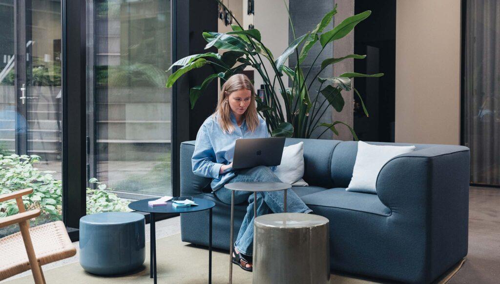 Woman sitting on sofa with a macbook